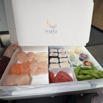 An open box of sushi held in hand